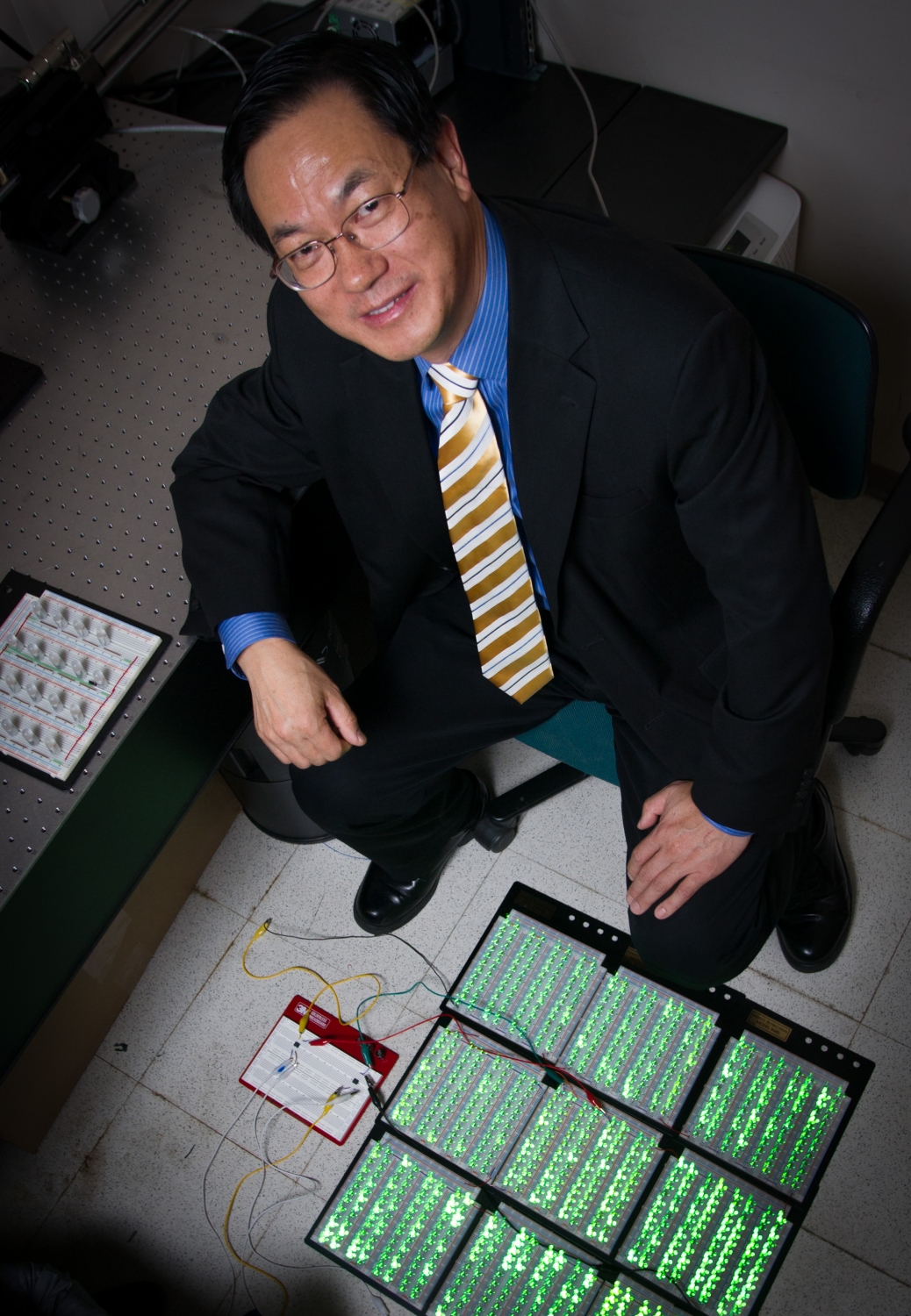 Georgia Tech professor Zhong Lin Wang poses with an array of 1,000 LED lights that can be illuminated by power produced by the force of a shoe striking a triboelectric generator placed on the floor. (Georgia Tech Photo Rob Felt).