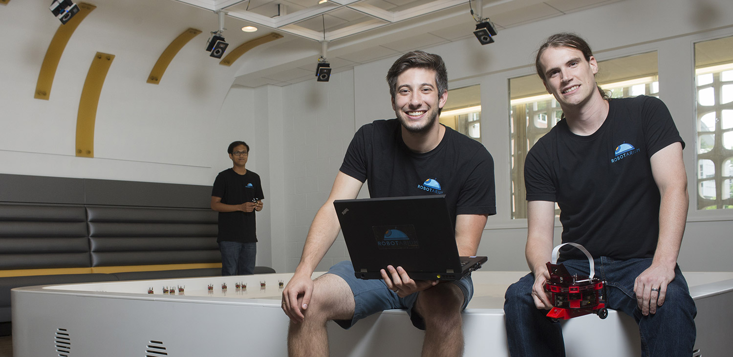 The robotarium build team smiling in the robotarium, holding hardware