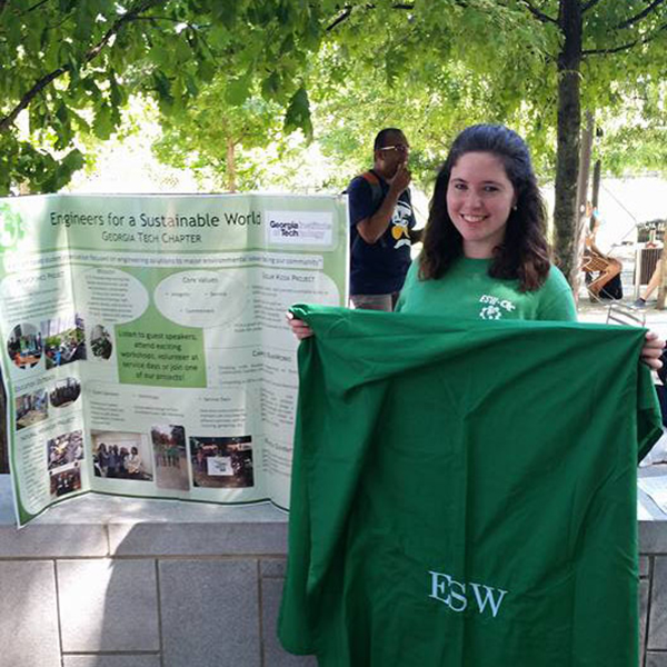 photo - young woman standing in front of a small outdoor exhibit with the title "Engineers for a Sustainable World".