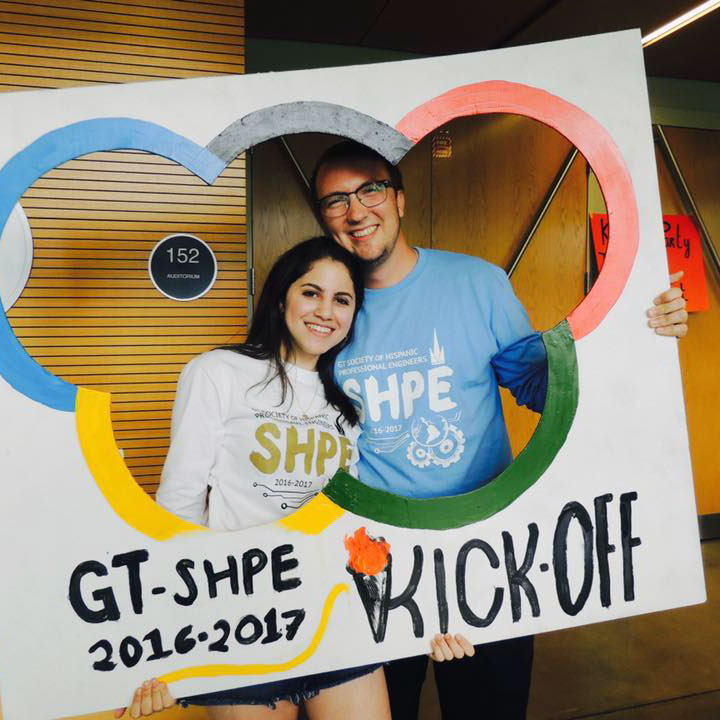 photo - two young people posing inside a large photo cutout with the words "GT-SHPE 2016-2017 kick-off"