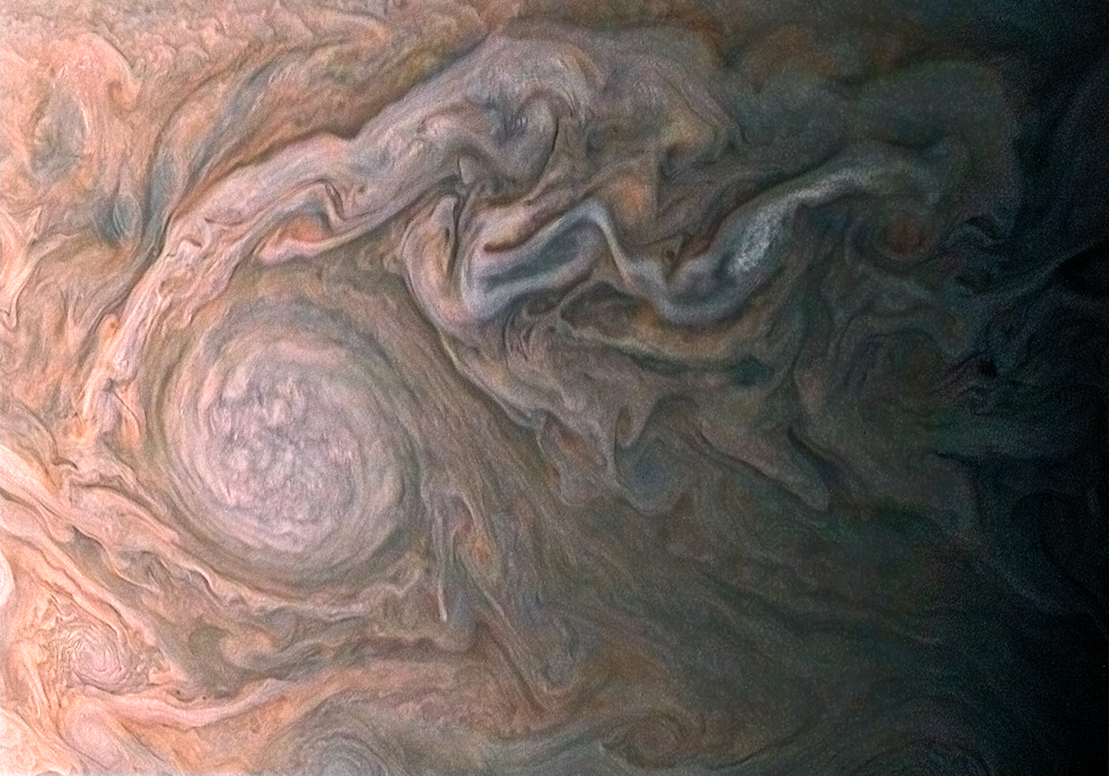 A closeup of the surface of Jupiter's atmosphere showing very detailed and chaotic bands of different colors