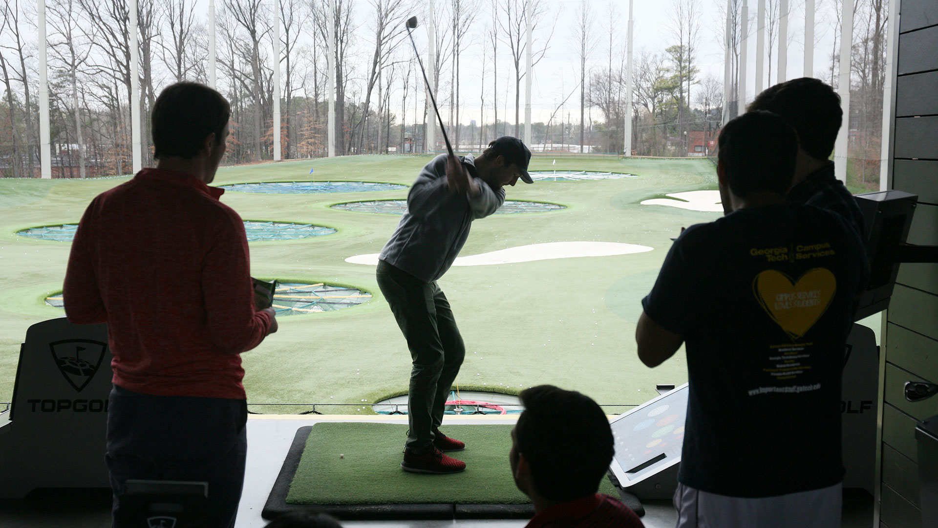 photo - group of students watching a fellow student at golf driving range