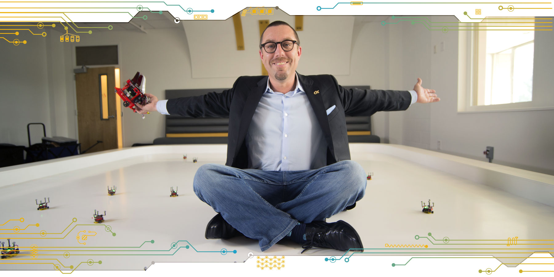 Magnus Egerstedt sitting on the robot stage in the Robotarium lab