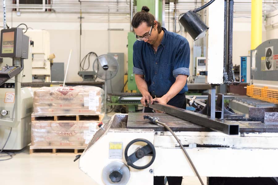 Technician Andrew Sickafoose saws a piece of steel square tubing that will be part of the frame for a cooling system for the military.