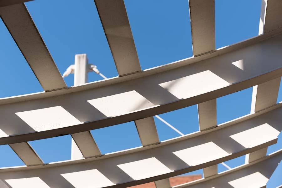 An open, inverted-arch canopy suspended from posts adorns the entry to the Penny and Roe Stamps Student Center Commons.