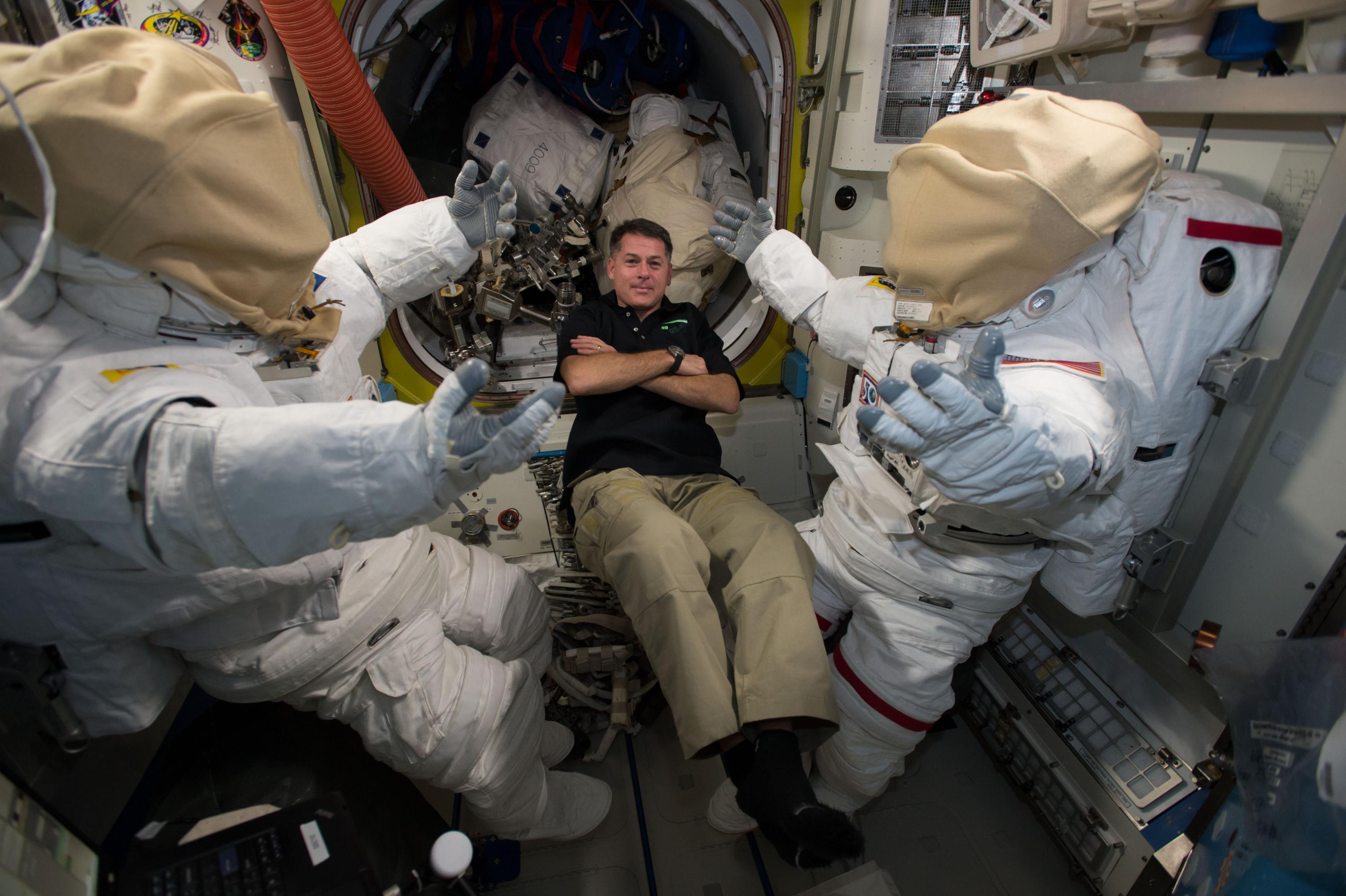 NASA astronaut Shane Kimbrough floats next to two U.S. spacesuits inside the Quest Airlock aboard the International Space Station.