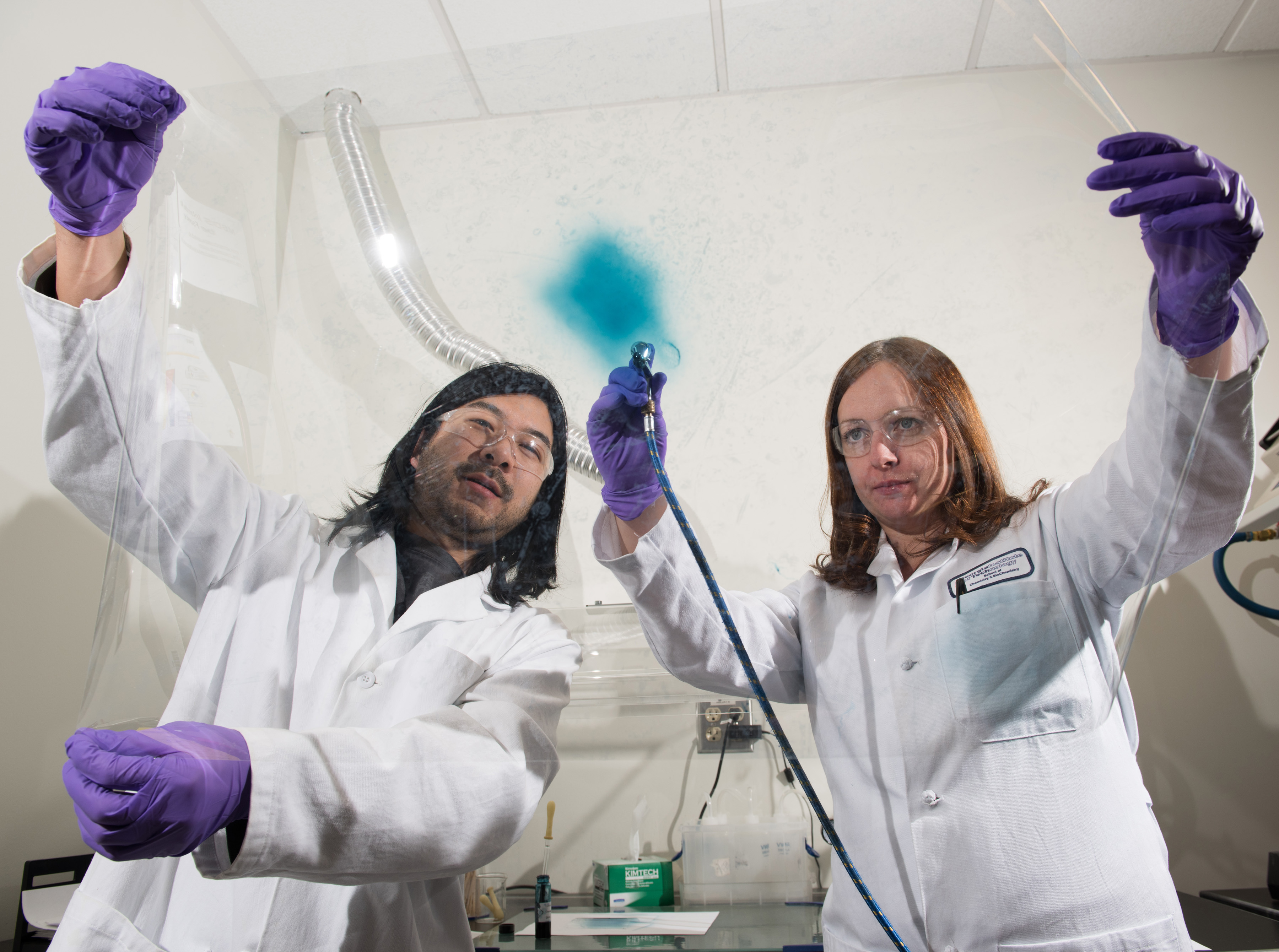 Georgia Tech researchers Eric Shen and Anna Osterholm demonstrate how films of electrochromic polymers can be applied to large surfaces. (Credit: Rob Felt) Georgia Tech researchers Eric Shen and Anna Osterholm demonstrate how films of electrochromic polymers can be applied to large surfaces. (Credit: Rob Felt)