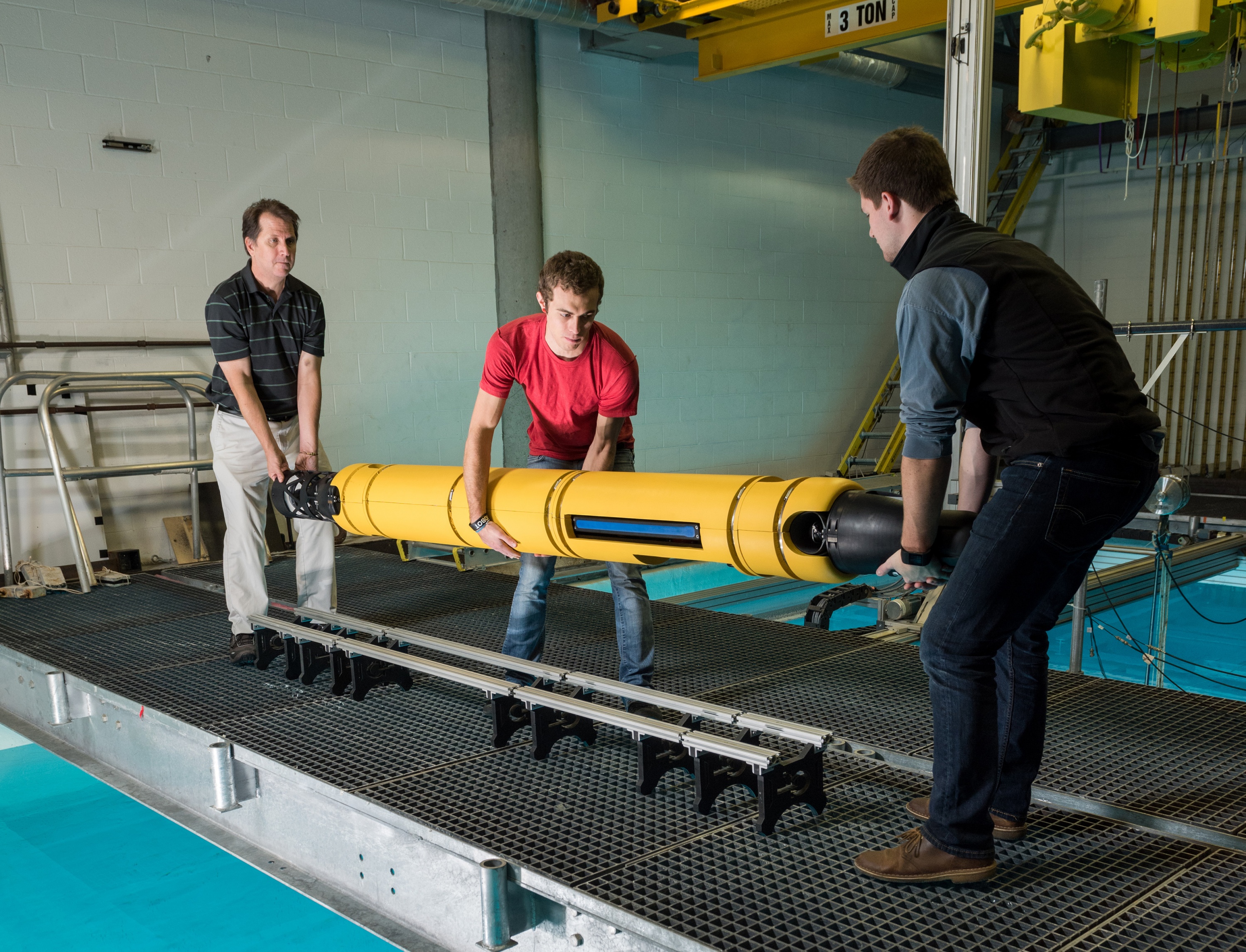 GTRI principal research engineer Mick West, graduate student Jacob Buffo of the School of Earth and Atmospheric Sciences, and undergraduate Matthew Meister of the School of Mechanical Engineering handle the 210-pound Icefin at Georgia Tech’s Underwater Acoustics Research Laboratory.
