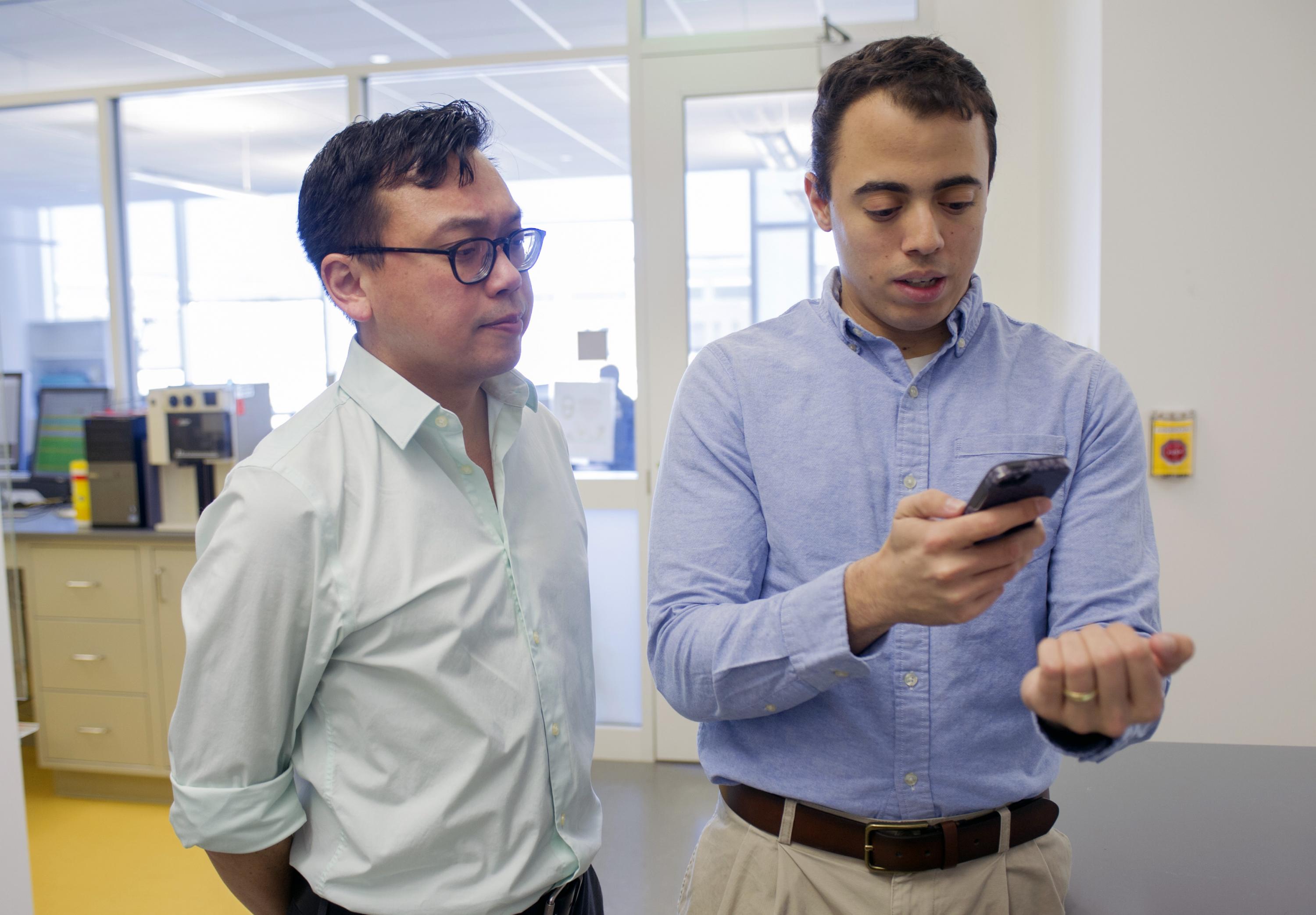 Graduate student Rob Mannino (right), pictured with Wilbur Lam (left), looks at his own fingernails using the new anemia test app. Credit: Georgia Tech / Christopher Moore