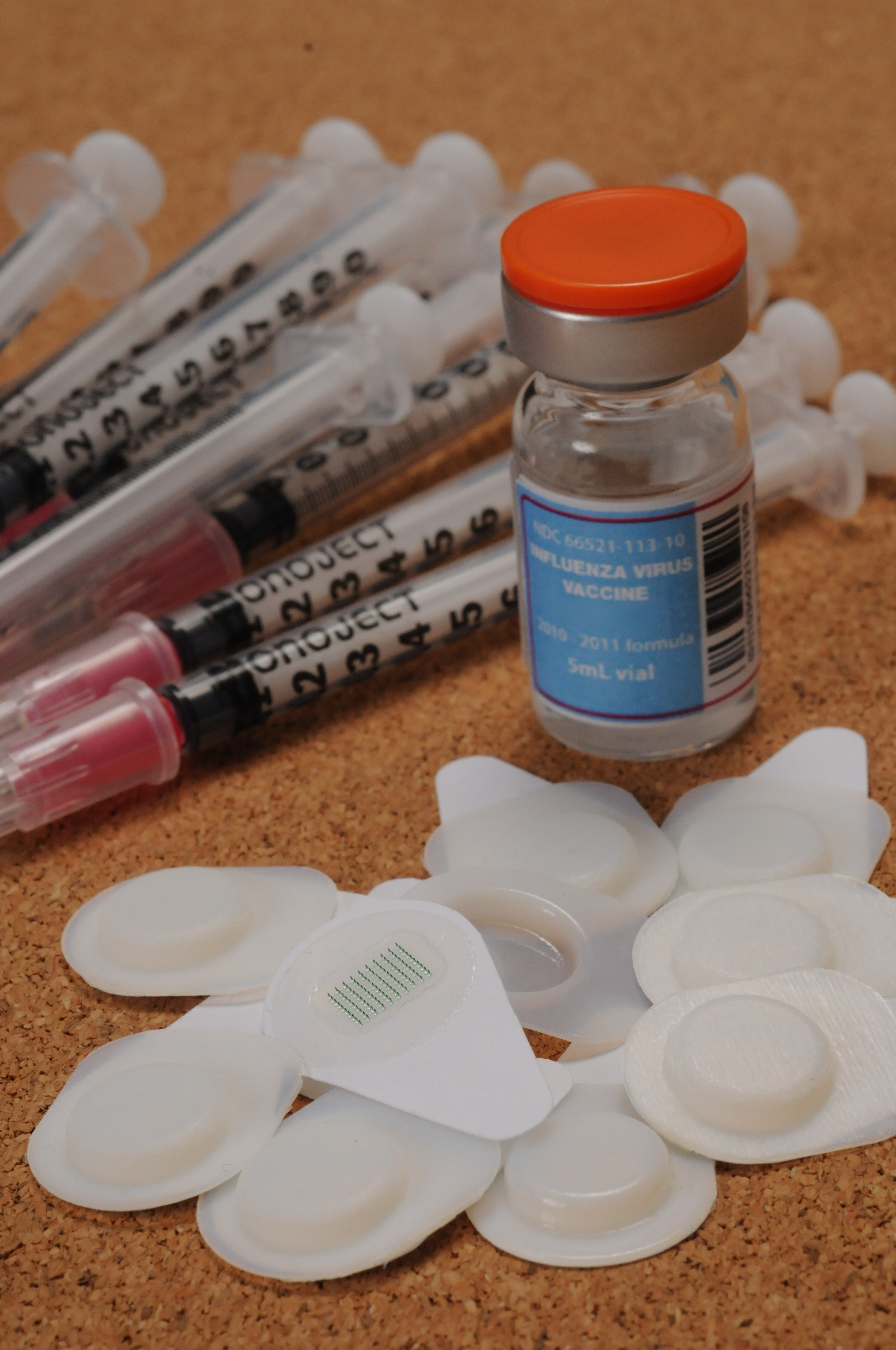 Ten microneedle patches are shown with a ten-dose vial of influenza vaccine and ten hypodermic needles with syringes. (Georgia Tech Photo: Gary Meek) Ten microneedle patches are shown with a ten-dose vial of influenza vaccine and ten hypodermic needles with syringes. (Georgia Tech Photo: Gary Meek)