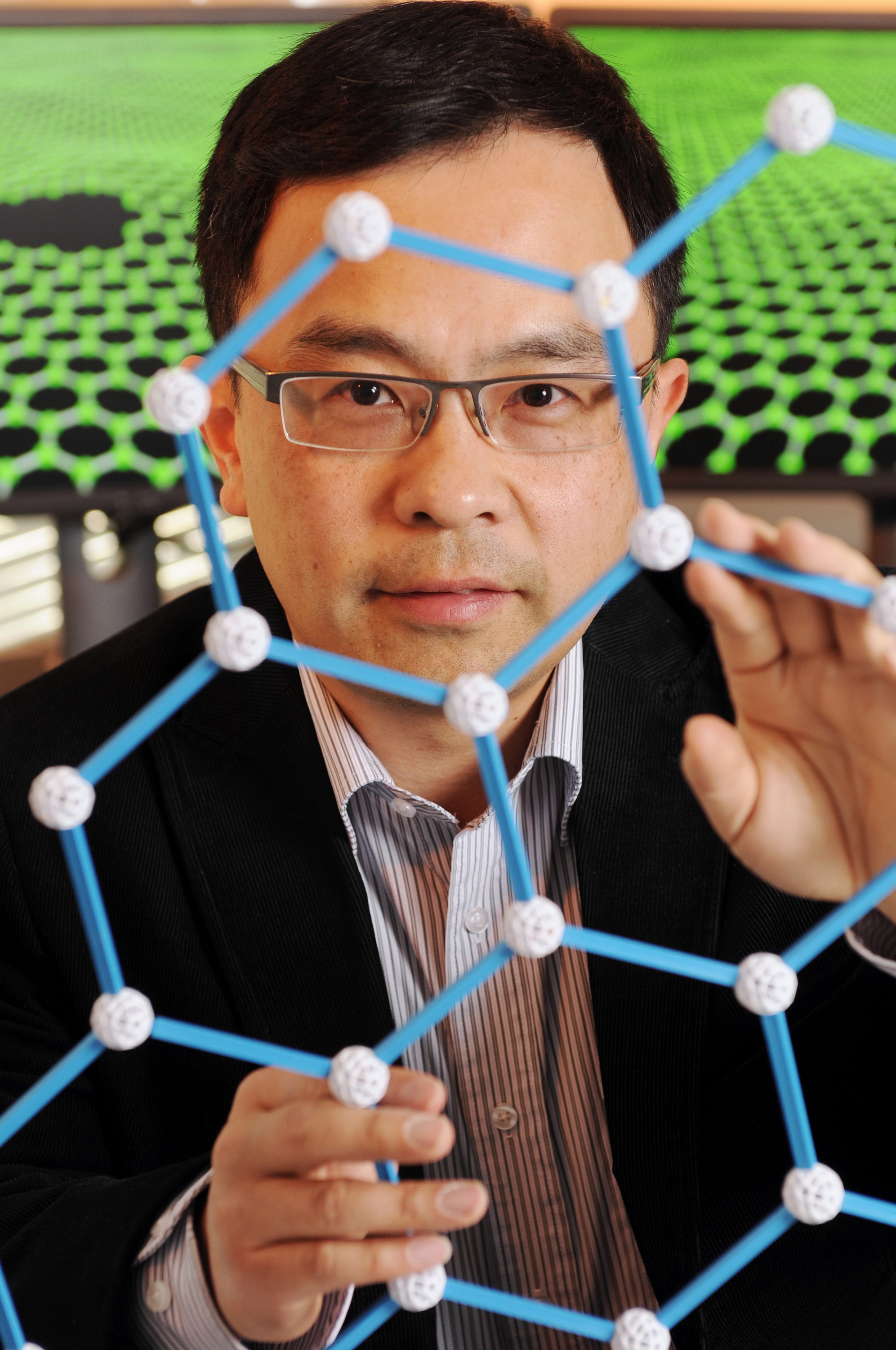 Ting Zhu an associate professor in the George W. Woodruff School of Mechanical Engineering at Georgia Tech, is shown with a model of the graphene structure. Georgia Tech's calculations and physical experiments at Rice University led to the conclusion that graphene, the one-atom layer of carbon, is only as strong as its weakest link. (Georgia Tech Photo: Gary Meek)