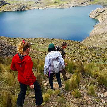 Georgia Tech students hike down a mountain towards a blue lake.