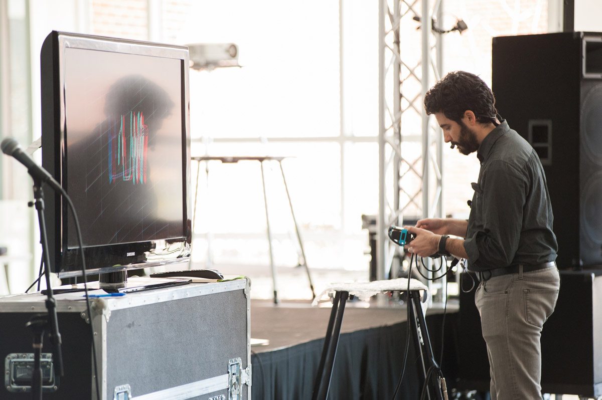 Man wearing headphones and using computer equipment, including a monitor, to create music