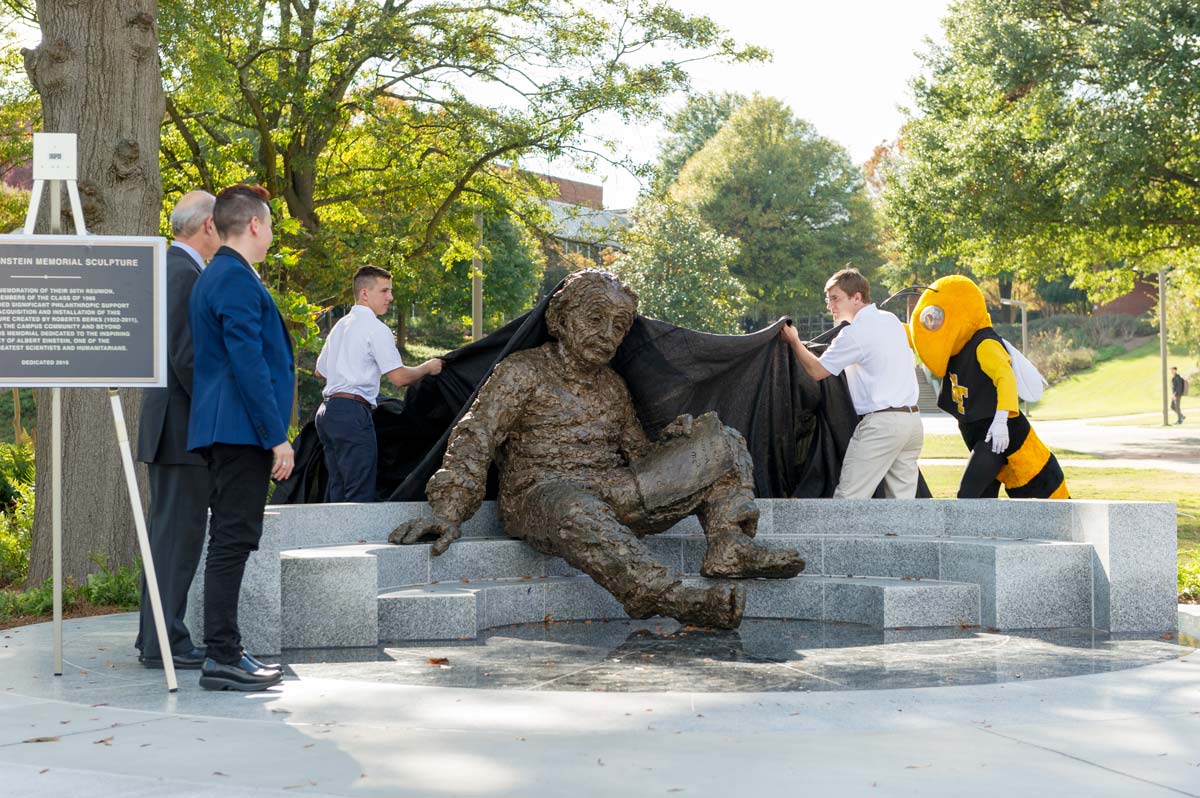 Students and Buzz lifting fabric off the Einstein sculpture
