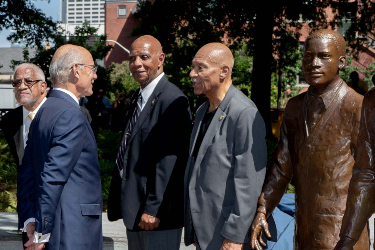 Candid photo of people standing around Trailblazers sculptures talking