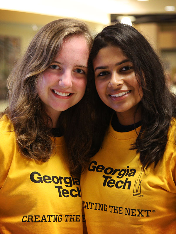 Two women at Freshman Convocation wearing "Creating the Next" T-shirts
