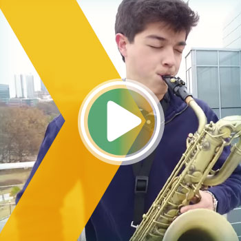Nicholas Doss playing bass saxaphone on a rooftop