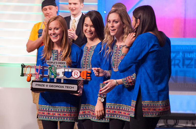 The TruePani team, four women wearing identical blue tunics, on stage with a large trophy that says "Inventure Prize"