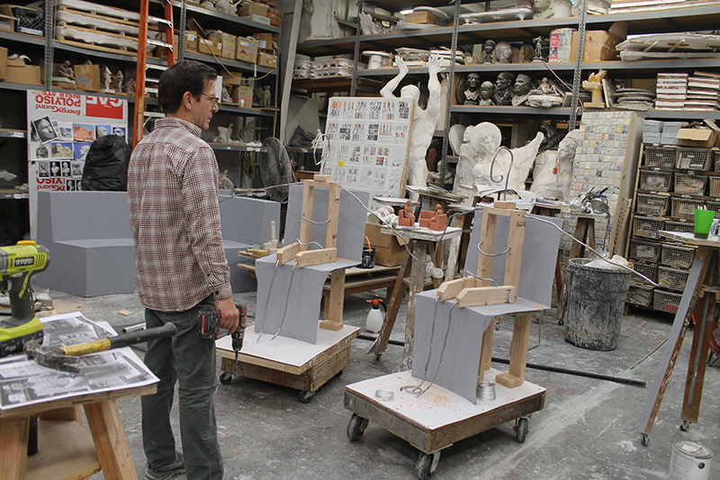 Sculptor in his studio studying the armature forms for the sculpture