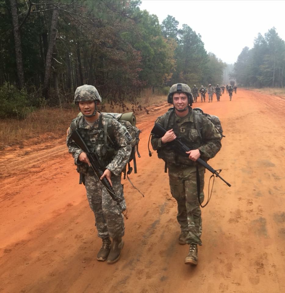 Two young men in combat gear carrying rifles during an Army training exercise