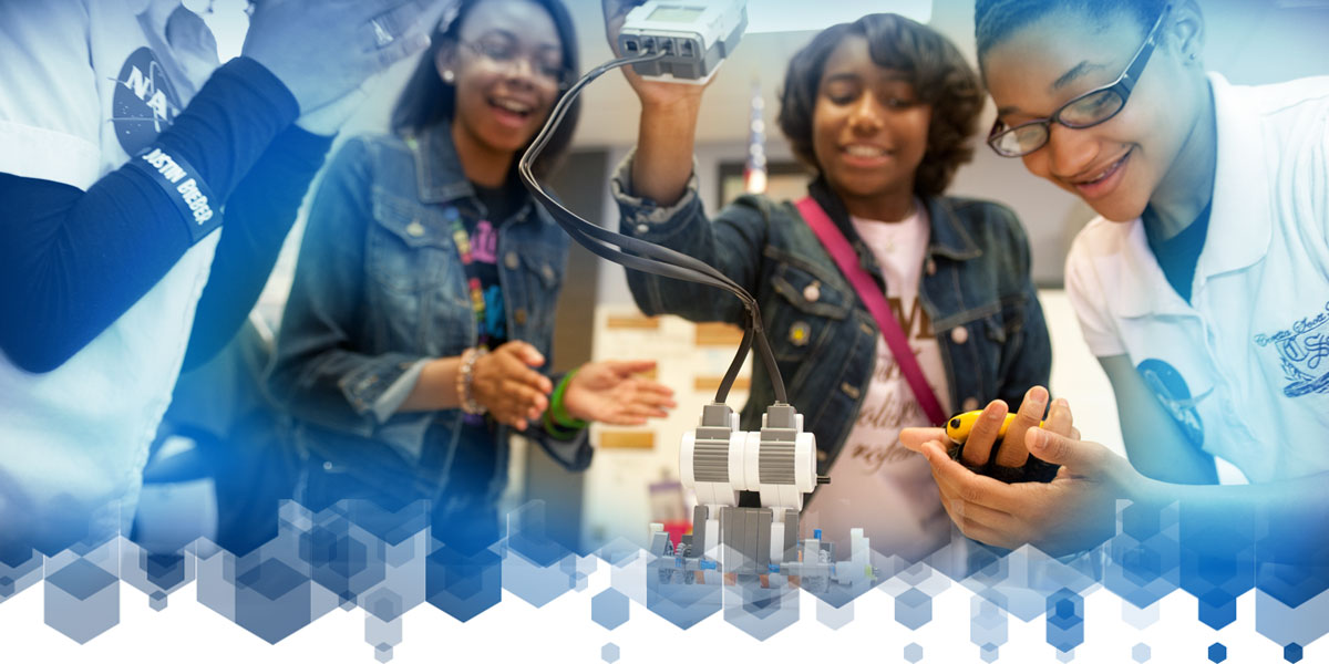 Several students at Coretta Scott King Young Women's Leadership Academy smiling and working with robots