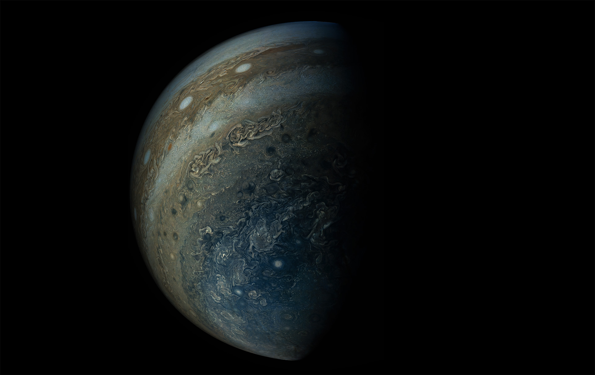 A full portrait of Jupiter showing the entire planet, with the right side in shadow, taken during Juno's sixth approach to the planet in May 2017.