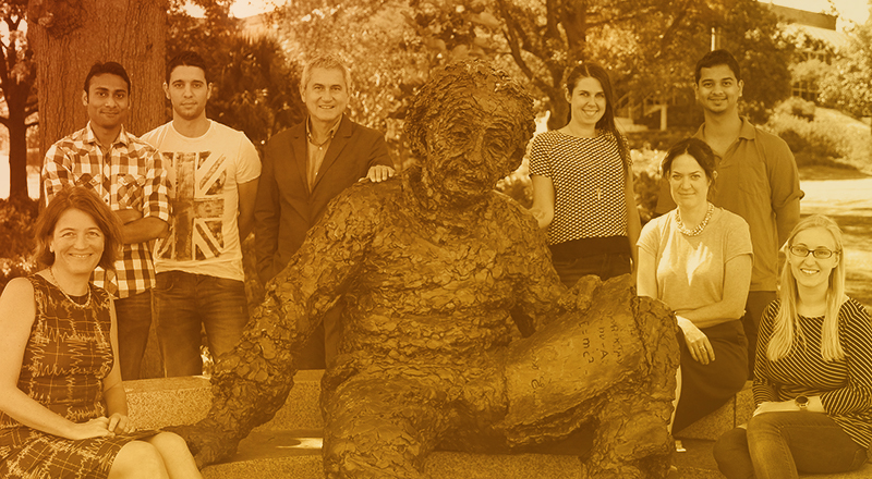 A group photo of eight members of the LIGO team, four of them women, at the Einstein statue