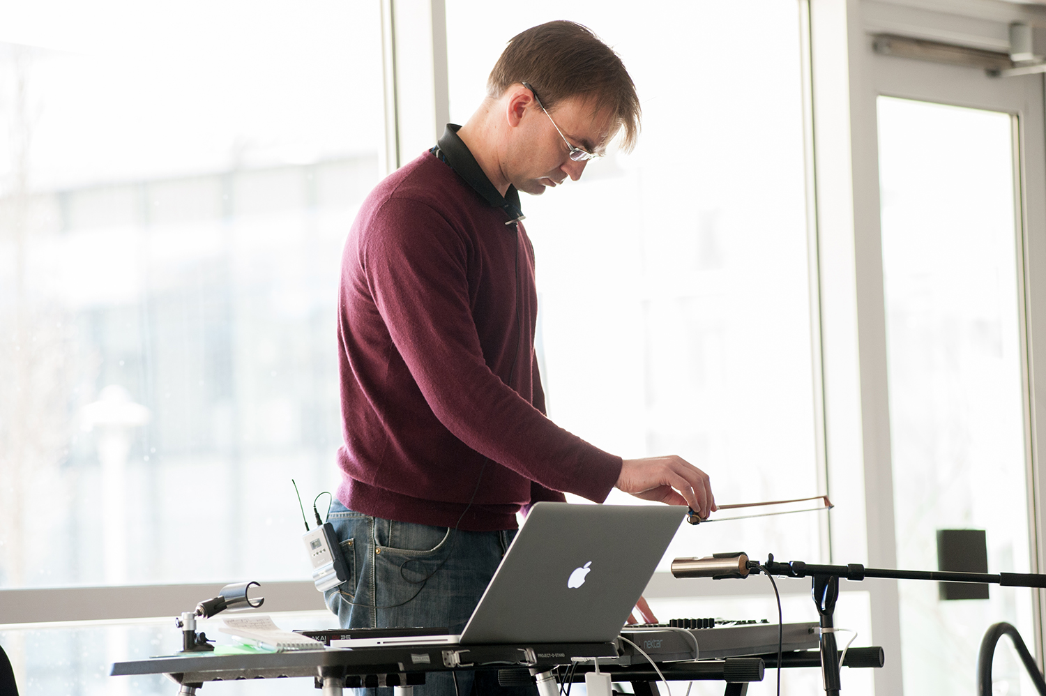 Man holding a bow above a small cylinder of metal to make music