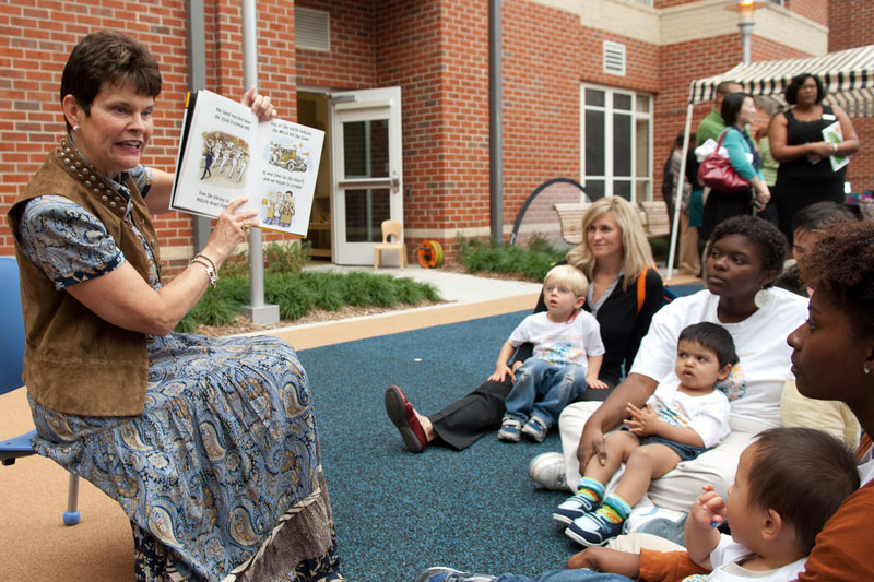 Val Peterson holding up a book for a group of children