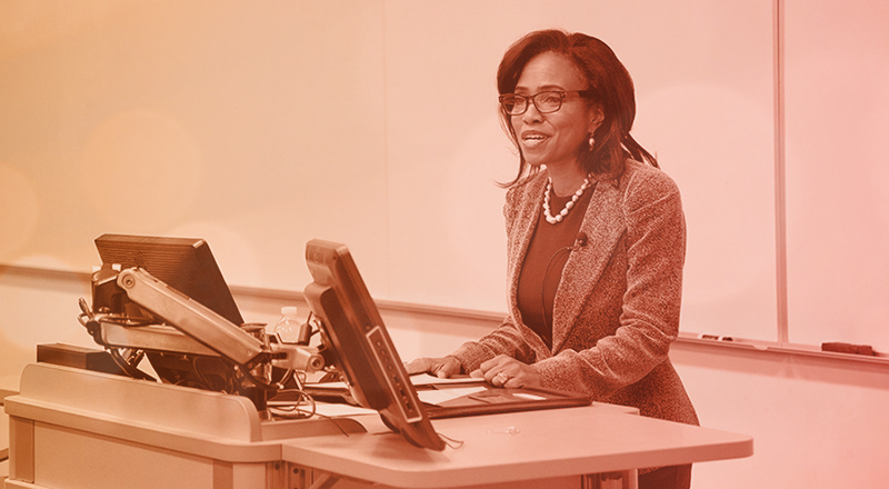 Suzanne Shank at a lectern in a classroom