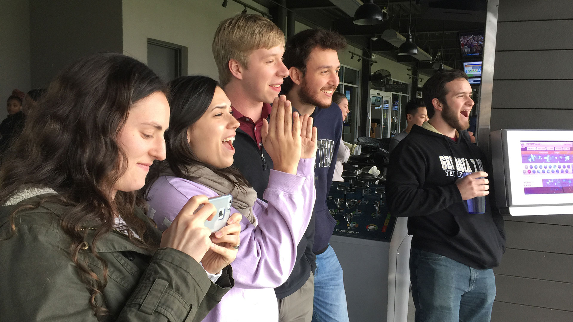 photo - group of students watching a fellow student at golf driving range
