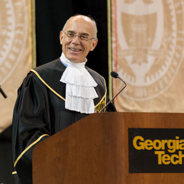 Provost Bras, in academic regalia, behind the podium at a commencement ceremony