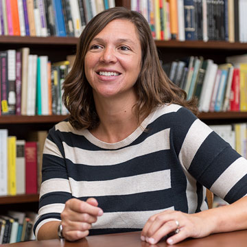 photo - Kelly Comfort seated in front of book shelves