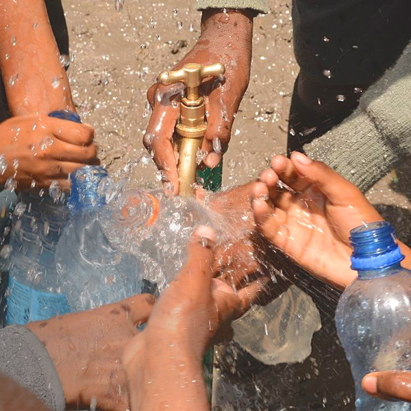 Hands under a water pump.