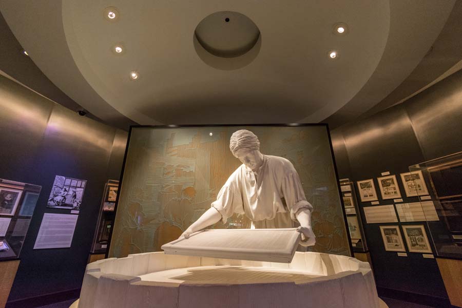 This statue portrays a papermaker using a mold and deckle to make paper.