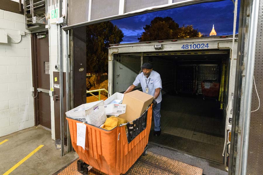 Dean A. Stratton, tractor trailer operator with the U.S. Postal Service, unloads a mail cart.