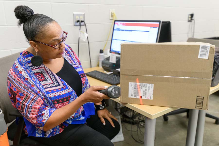 Felice Albany, supervisor at the Student Center Post Office, scans packages and enters the student’s name and mailbox number into the system.