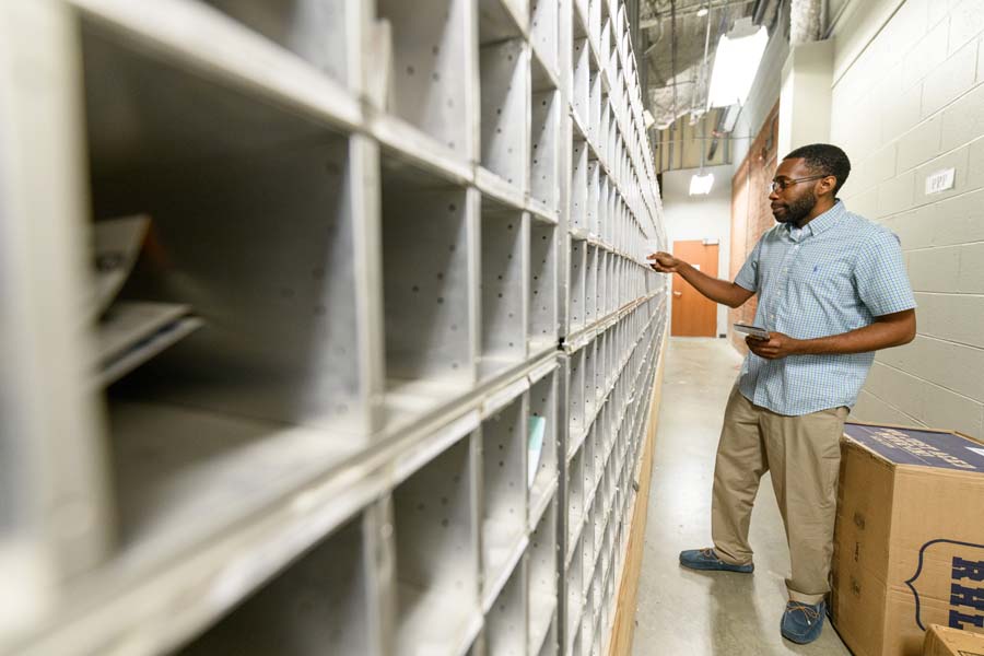 Kristopher Johnson, postal services clerk lead, puts mail into the boxes. The beginning of fall and spring semesters are peak times for mail delivery.