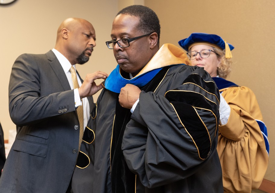 Faculty members assist each other in donning regalia for the event.