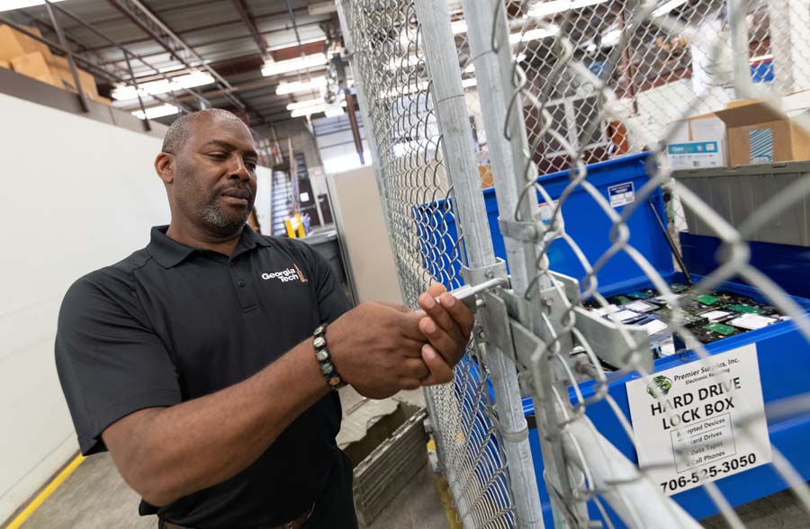Kenneth Chavers, logistics surplus manager, secures the lock on a cage holding surplus hard drives that may contain sensitive data.