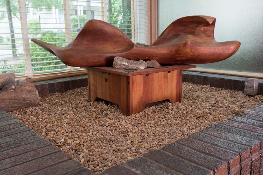 Five plate glass windows cover the entire front of the house. The original outside brick is still inside, forming part of the main entry that features a large wooden sculpture.