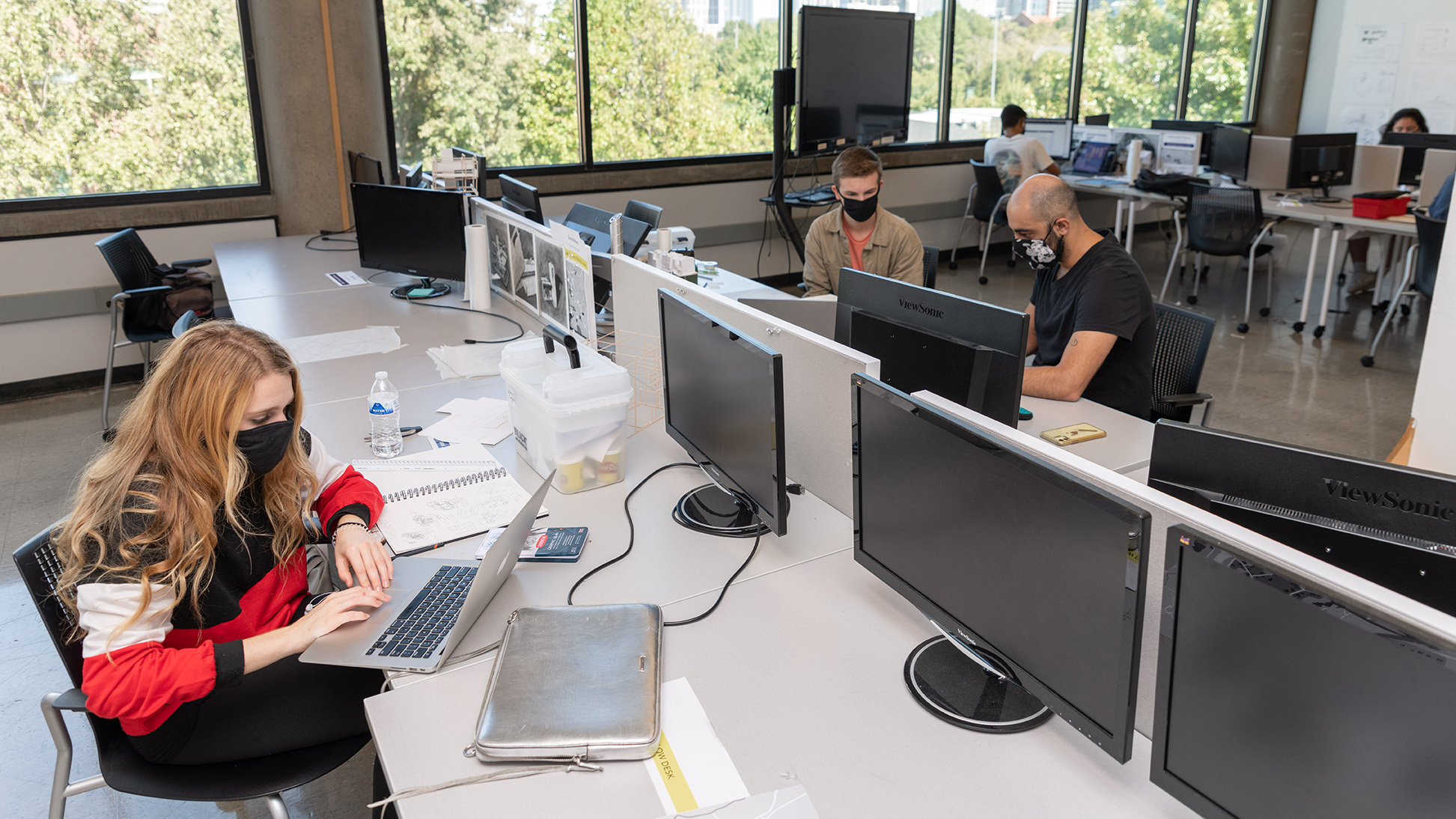 Students Julianne Coughlin and Adam Davis and teaching assistant Yousef Bushesri take preventive measures while working in the Architecture Building.