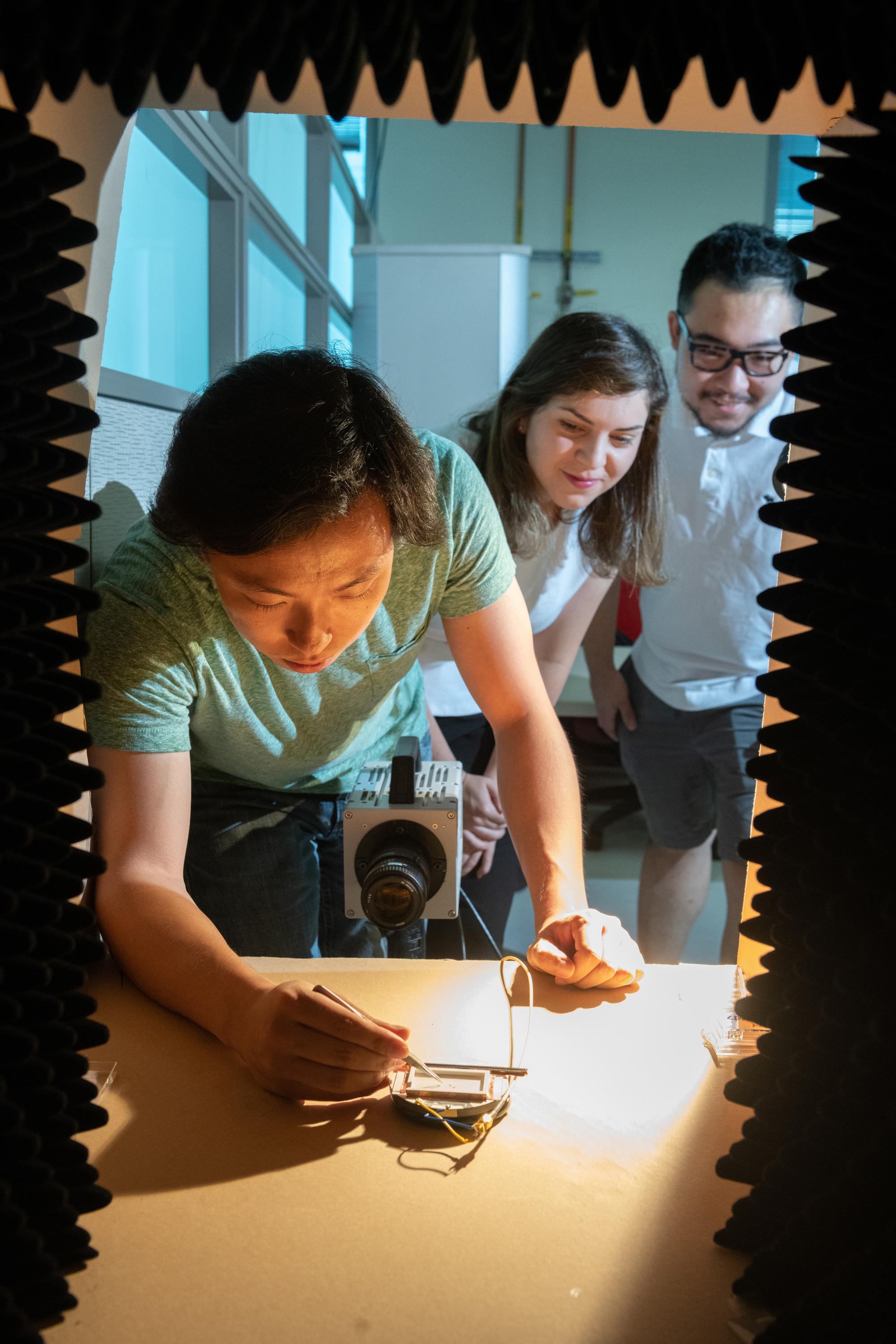 Georgia Tech researchers Azadeh Ansari, DeaGyu Kim and Zhijian (Chris) Hao test a micro-bristle-bot in a chamber designed to contain the sound of the piezoelectric actuator. (Photo: Allison Carter, Georgia Tech)