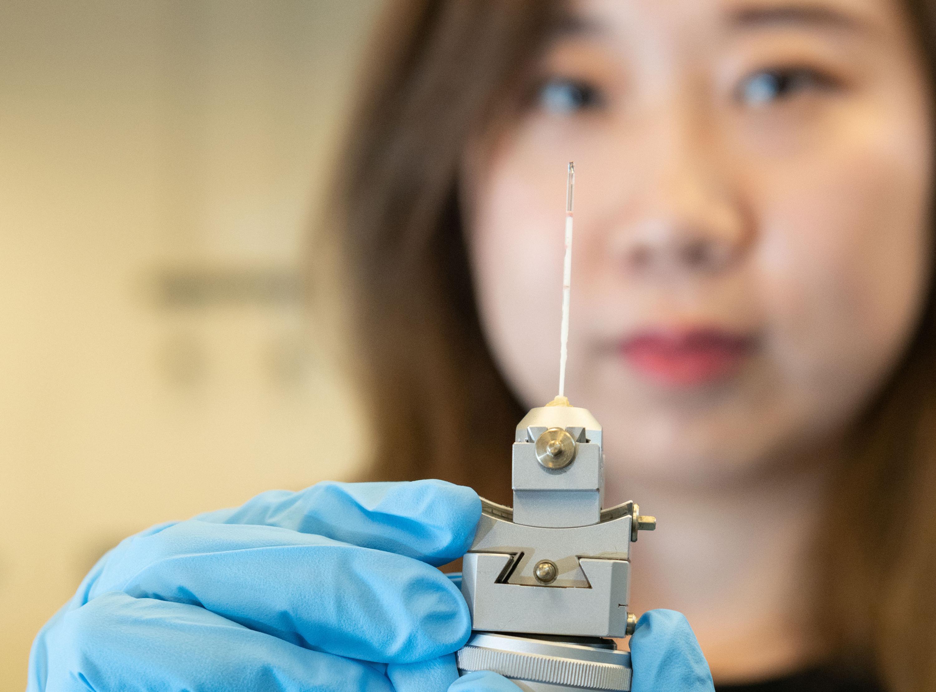 Georgia Tech graduate research assistant Xuetian Ma holds a reaction vessel similar to those used in the research on nanoscale crystalline growth. The vessels were made of a high-strength quartz tube about a millimeter in diameter and about two inches long. (Credit: Allison Carter, Georgia Tech)