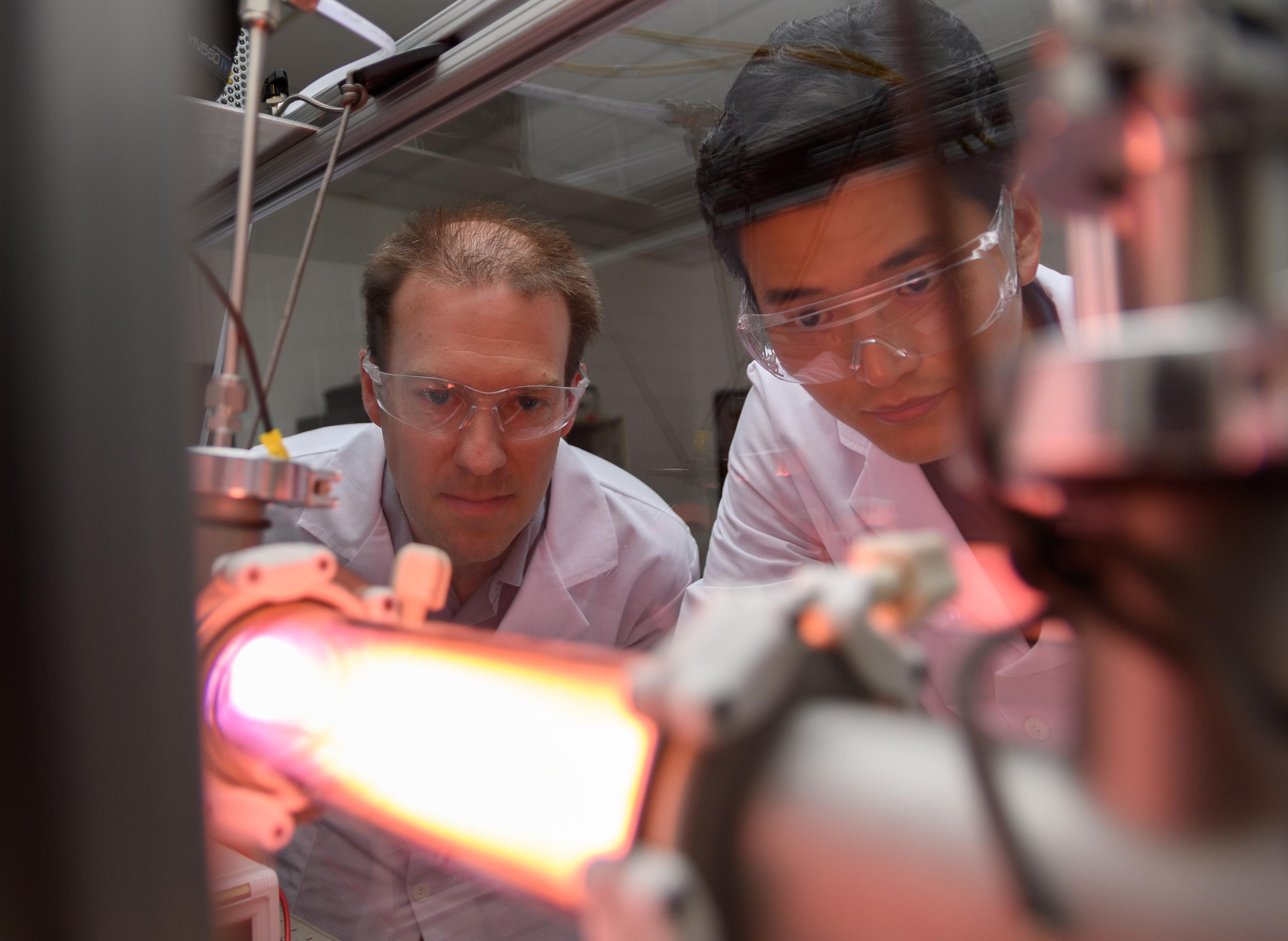 Georgia Tech Professor Lukas Graber and Postdoctoral Fellow Chanyeop Park study the plasma potential surrounding materials being evaluated for use in improved DC circuit breakers. The low-energy argon plasma creates the purple color. (Photo: Rob Felt, Georgia Tech)