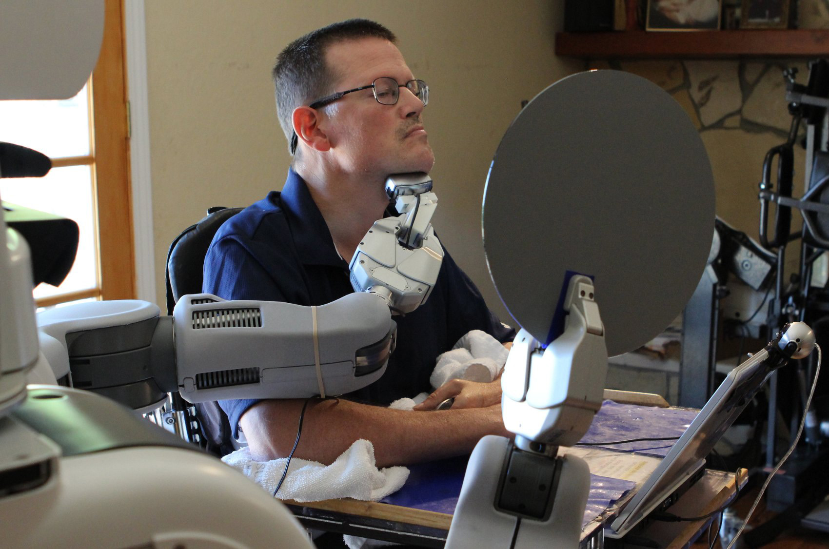 Charlie Kemp, director of the Healthcare Robotics Lab, working with Henry Evans, who lives with quadriplegia. As part of the Robots for Humanity project Evans briefly used a robot to shave. Evans is at his home using the robot.
