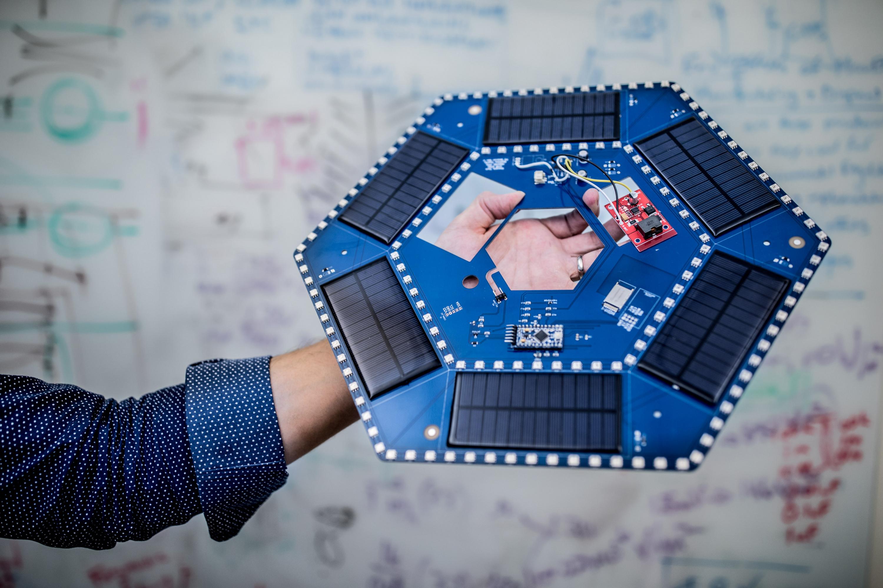 Ilan Stern, a GTRI senior research scientist, holds examples of the electronic components that will be used in piezoelectric tiles that will be used to create a lighted outdoor footpath at the NASA Kennedy Space Center’s Visitor Complex at Cape Canaveral, Florida. The tiles are powered by piezoelectric components that generate current when they are compressed, flexed or vibrated. (Credit: Branden Camp, Georgia Tech)
