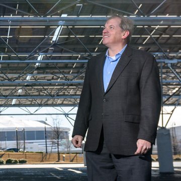 Norman “Finn” Findley, CEO of the startup Quest Renewables, stands beneath his company’s QuadPod Solar Canopy system. Solar canopies are high ground-clearance structures designed for solar panels, but they also function as carports by providing shade for vehicles parked beneath them.