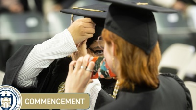 A student adjusts their mortar board at Commencement